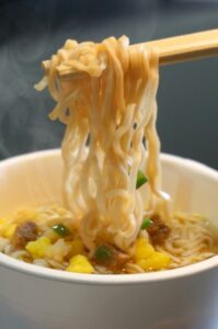 カップラーメンの麺を箸で持ち上げている