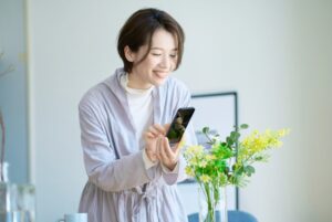 生けた花の写真を撮る女性