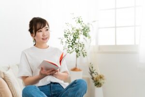 家のソファで本を読む日本人女性