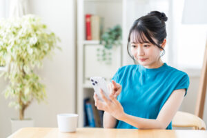 部屋でスマホを操作する若い女性